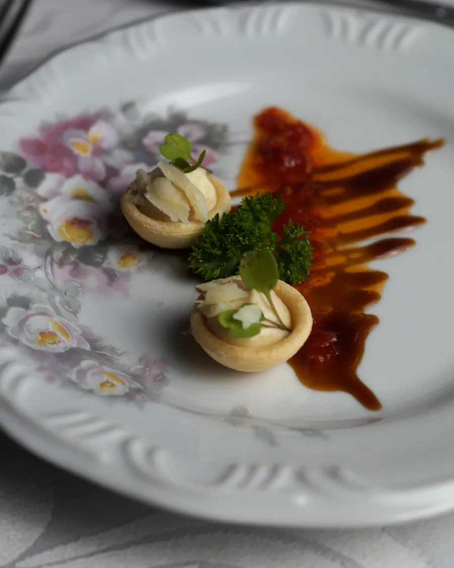Complemento do couvert: duas massinhas crocantes recheadas com creme de cogumelos, rillette e salsa crespa em prato de porcelana florida