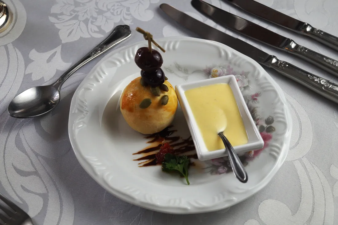 Couvert visto de cima: pão de batata artesanal com azeitonas pretas e creme de queijo emmental no ramequim